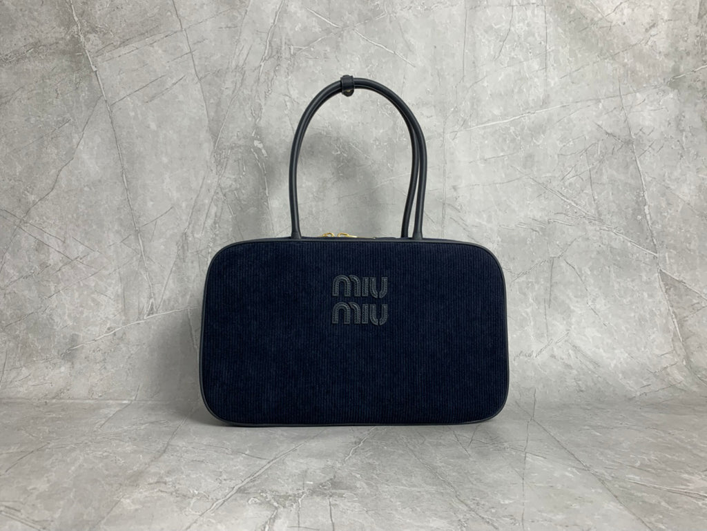 Dark navy vertically ribbed bag with rounded rectangular silhouette and elongated twin handles