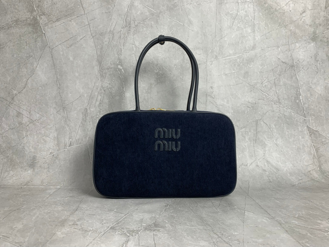 Dark navy vertically ribbed bag with rounded rectangular silhouette and elongated twin handles