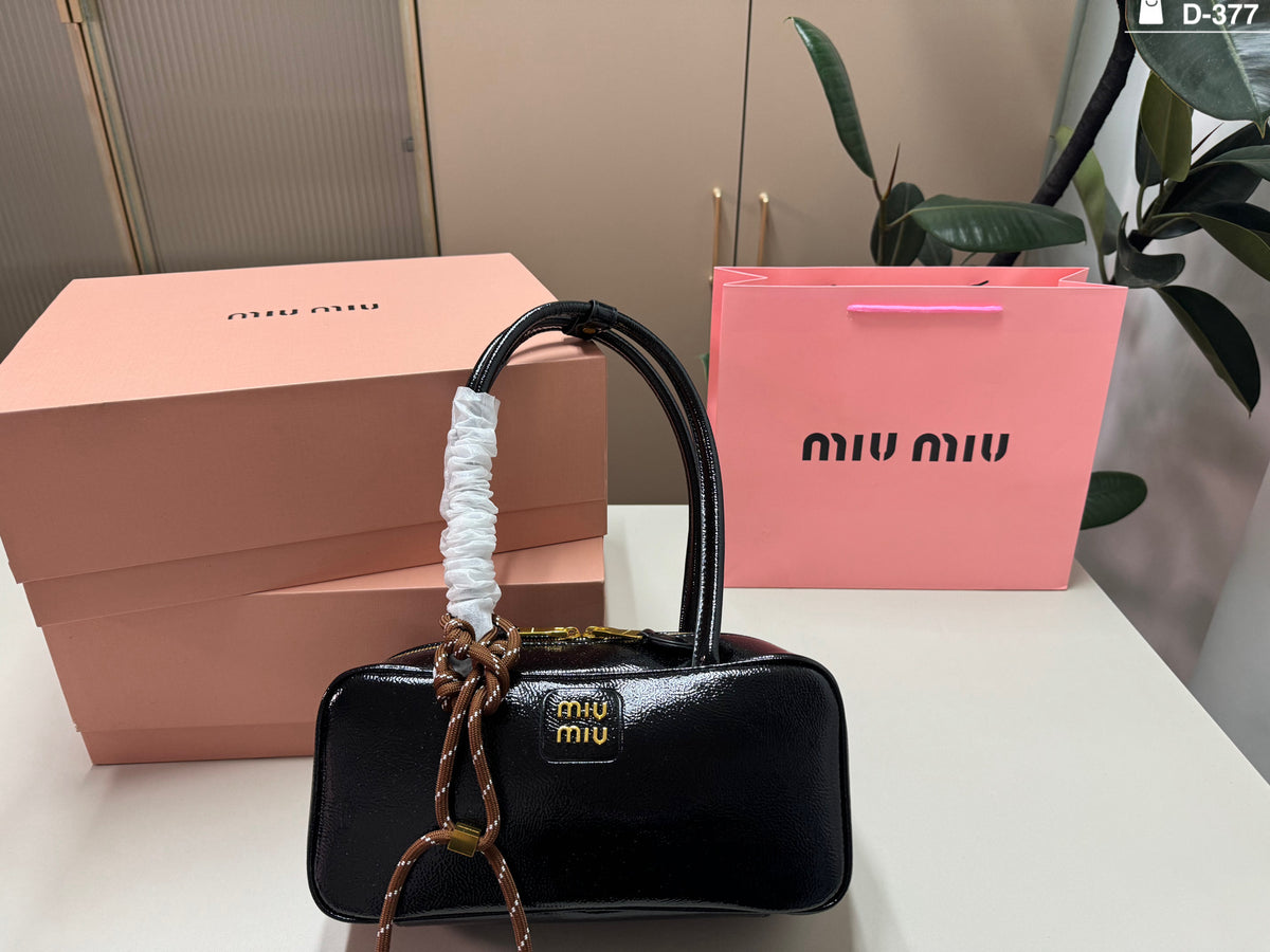 Glossy black rectangular bag with twin handles and gold-tone zip detailing