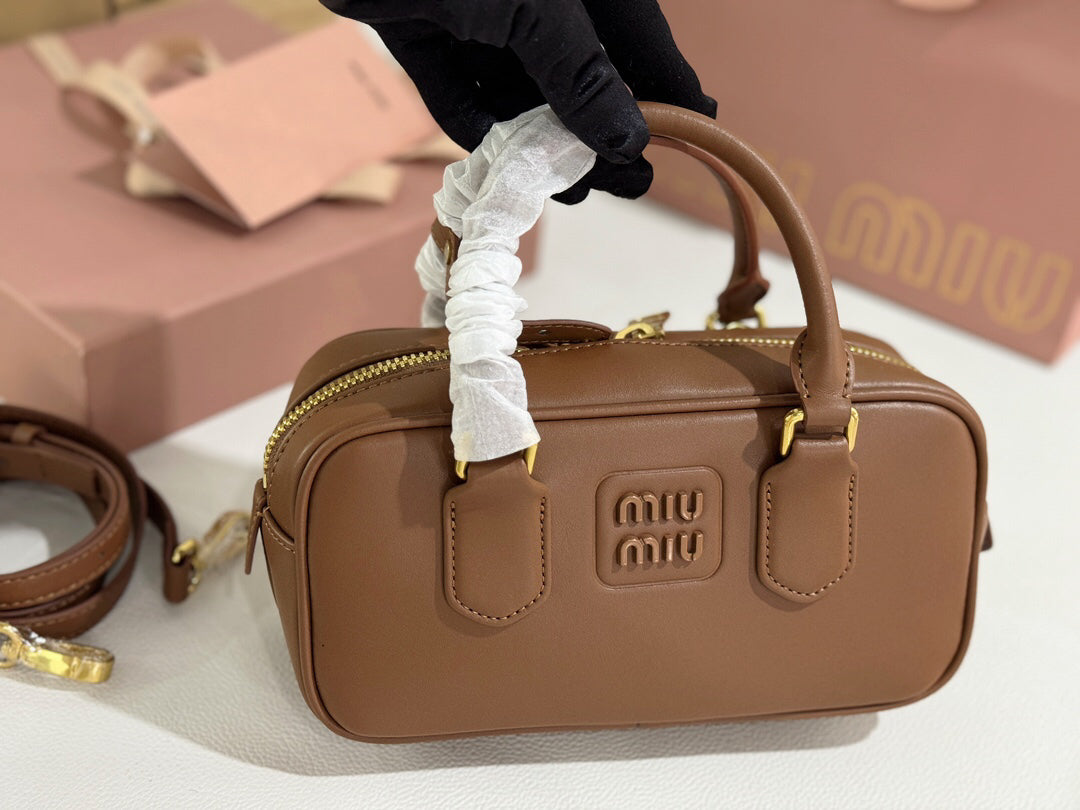 Caramel brown rounded rectangular bag with twin top handles and gold-tone zip detailing